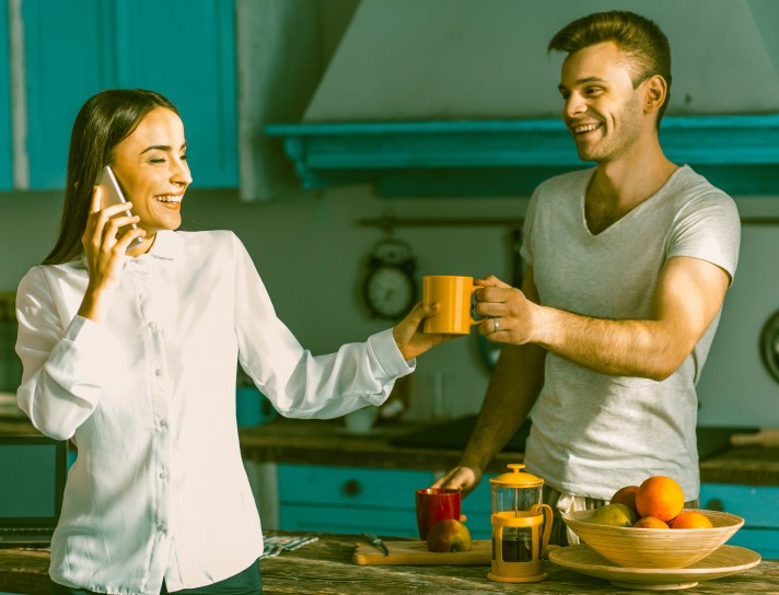 Happy couple chatting in the kitchen on sunny morning